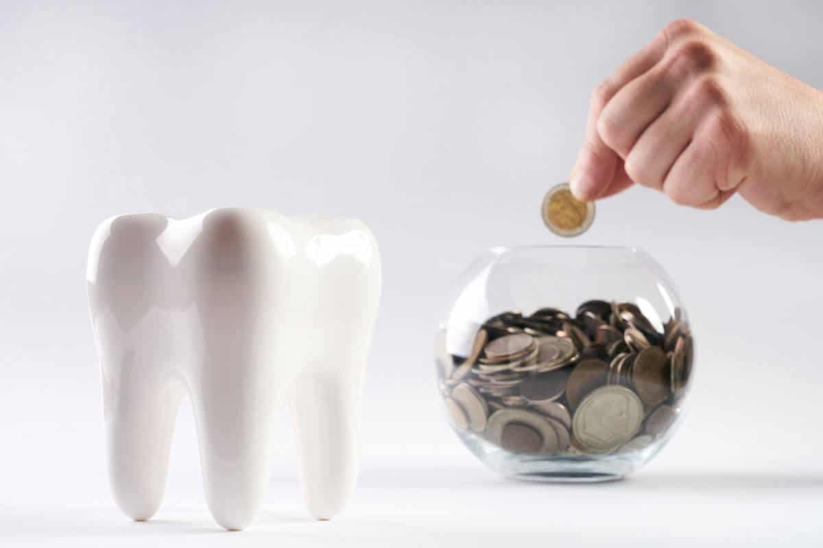 putting coins in a glass, with a tooth model beside it