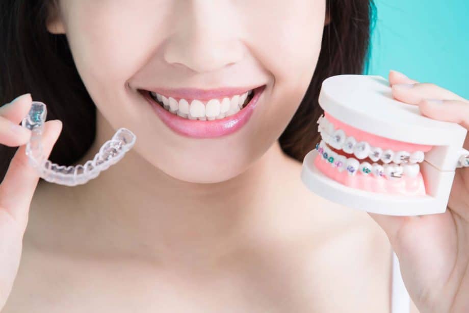 girl holding invisalign and traditional braces