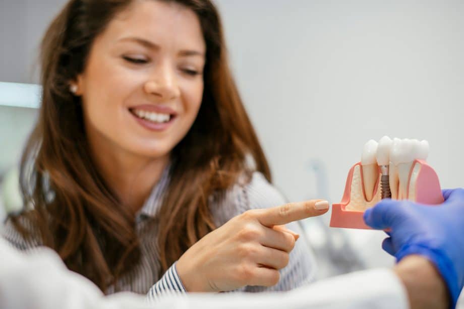 woman looking at model of tooth implant